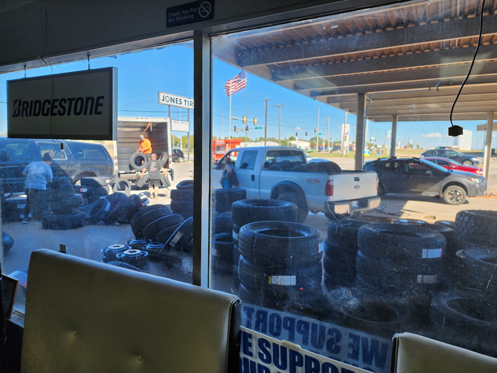 Crew unloading a delivery truck of tires outside Jones Tire